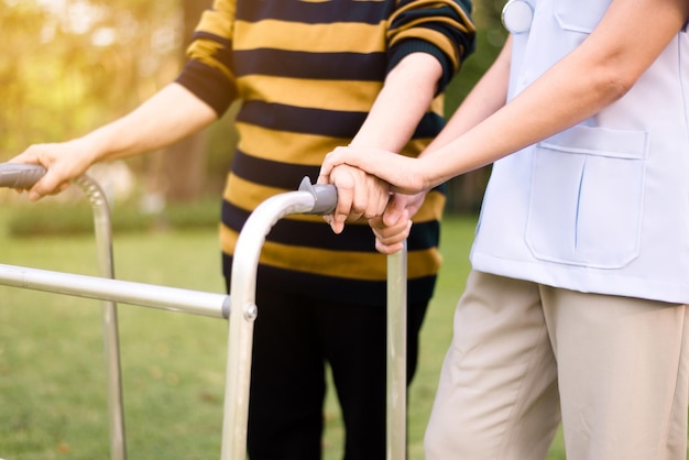 Enfermera ayudando a una anciana con las manos sosteniendo un andador tratando de caminar al aire libre Concepto de hogar de ancianos de cuidado Fisioterapia