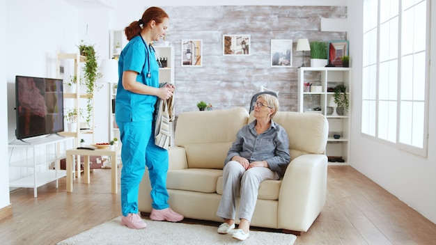 Enfermera ayudando a la mujer mayor a vestirse en un hogar de ancianos