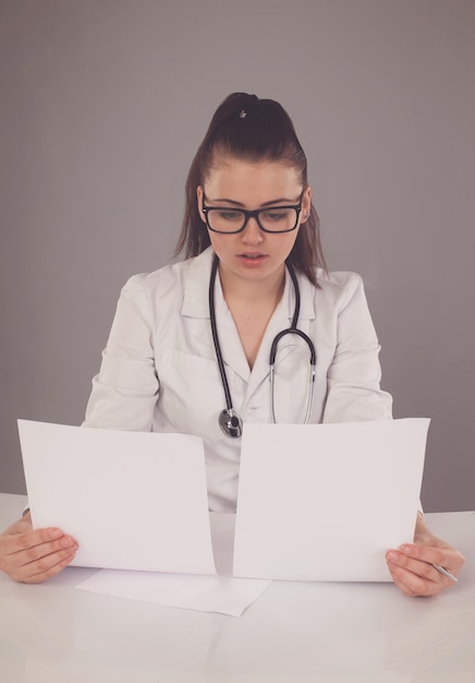 Foto la enfermera con bata blanca y anteojos está escribiendo su informe y pensando en ello en la mesa blanca