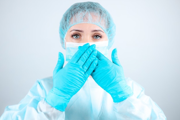 Una enfermera con bata médica, mascarilla y guantes protectores se tapó la boca con las manos.