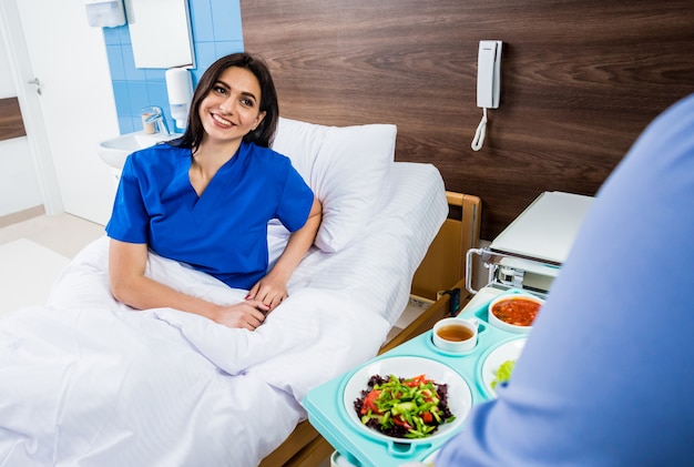 Enfermera en bata médica sostiene una bandeja con desayuno