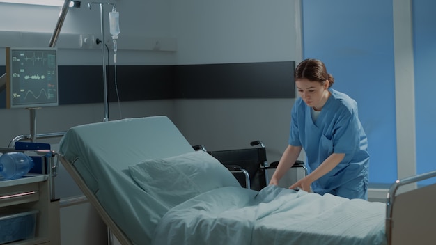 Enfermera caucásica haciendo cama de hospital para su uso