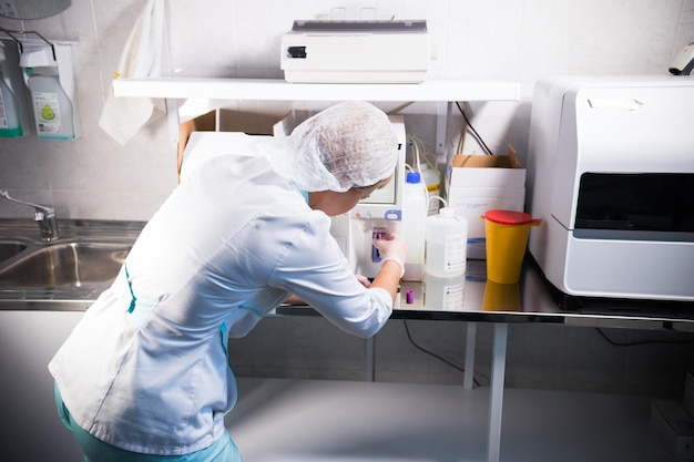 Foto la enfermera de la clínica médica trabaja con una máquina especial para el análisis de sangre