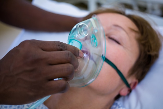 Enfermera colocando una máscara de oxígeno en la cara de un paciente
