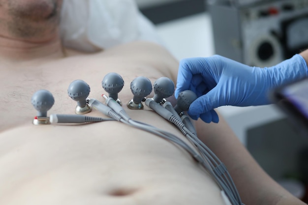 Enfermera colocando ventosas en el pecho del paciente para registrar el primer electrocardiograma