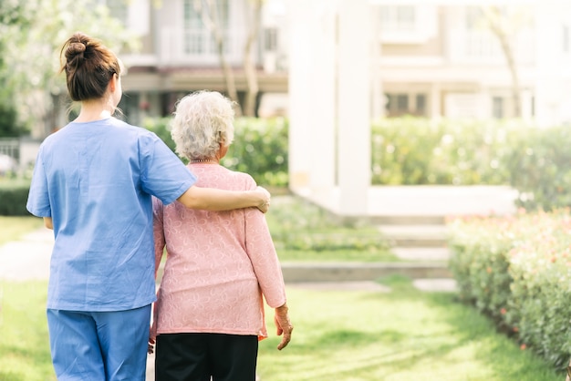 Enfermera cuidador apoyo caminando con anciana al aire libre