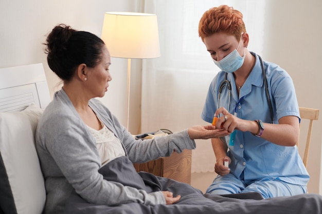 Foto enfermera dando pastillas para pacientes enfermos