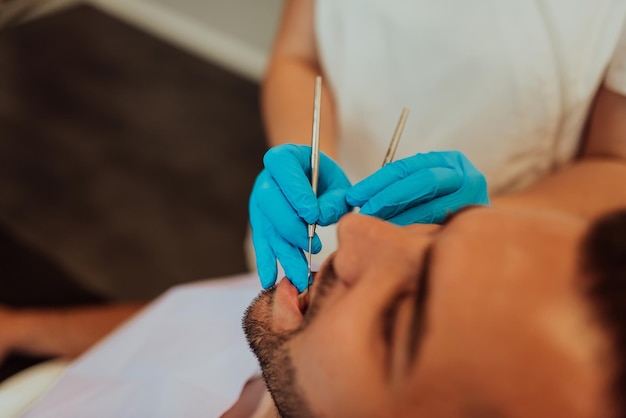 Enfermera dentista revisando la boca del paciente analizando la infección de los dientes usando un instrumento de taladro estomatológico durante el examen de ortodoncia en la sala de la oficina dental. Concepto de procedimiento odontológico. Alta calidad