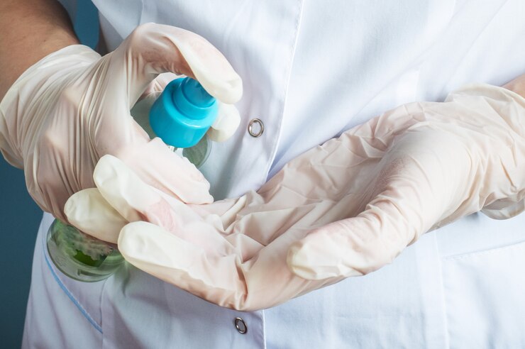 Una enfermera desinfecta las manos con guantes médicos de látex con una solución de limpieza.