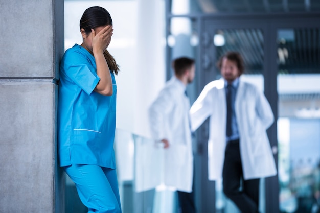 Foto enfermera estresada de pie en el hospital