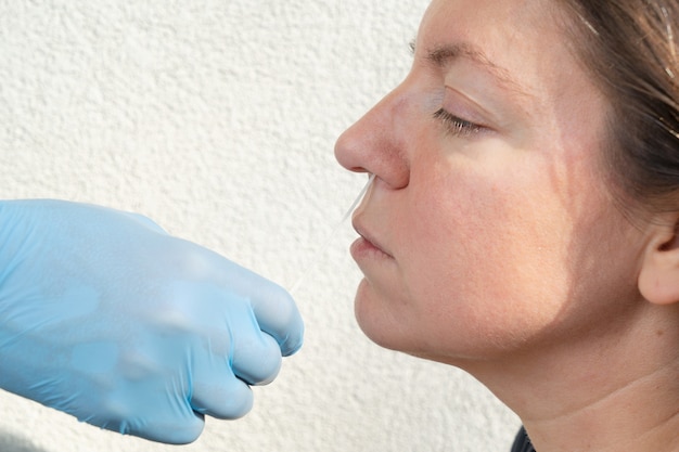 Enfermera con guantes azules hace una prueba de coronavirus nasal a una mujer