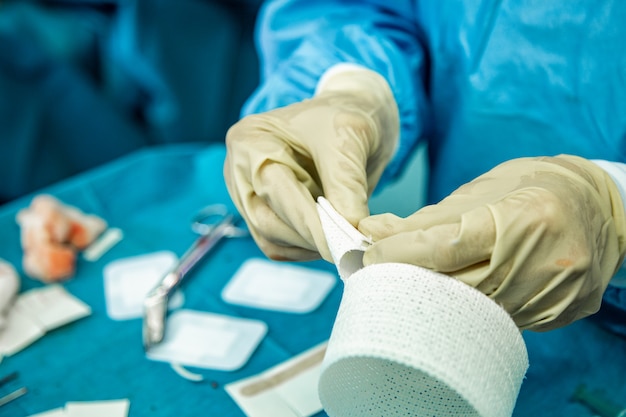 Foto la enfermera con guantes de látex corta tiras de vendaje en preparación para atender a una persona lesionada.