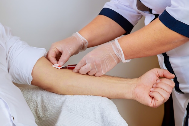 La enfermera de los guantes de medicina toma la sangre en el tubo de ensayo, muestra de sangre humana para COVID-19