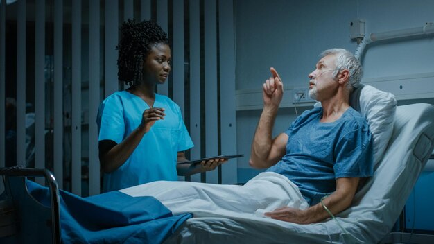 Foto una enfermera habla con un paciente en una cama de hospital.