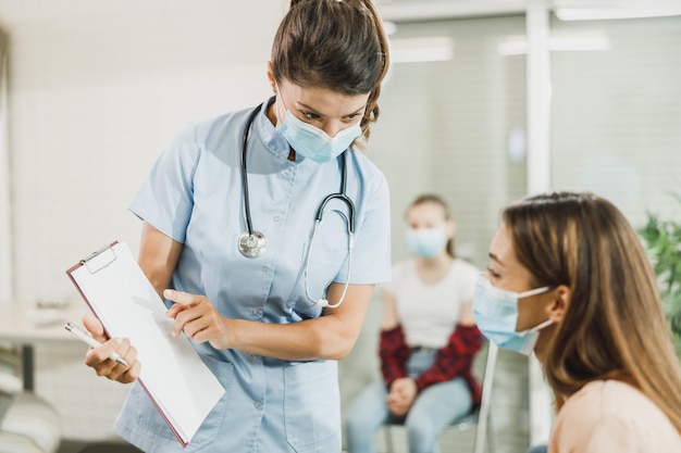 Enfermera hablando con una joven antes de la vacuna covid-19 en la sala de espera del hospital.