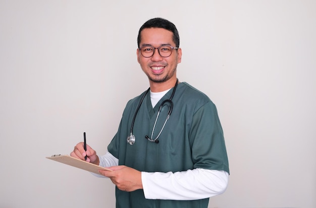 Enfermera del hospital asiático sonriendo amablemente mientras sostiene un bolígrafo y un portapapeles