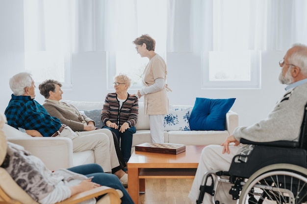 Foto la enfermera jefe habla con nuevos pacientes sentados en el sofá de una residencia de ancianos