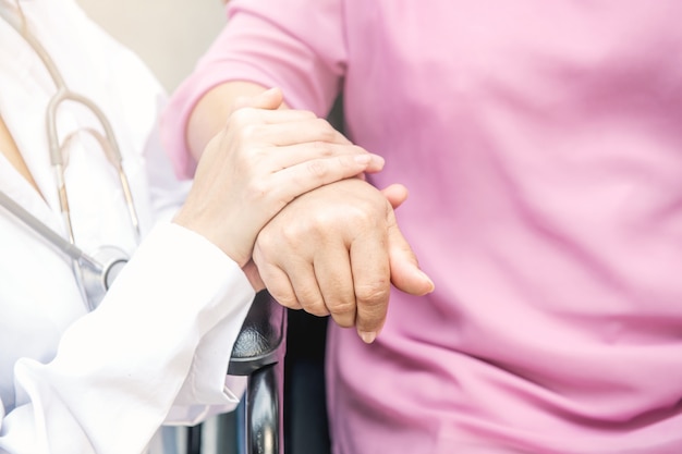 Enfermera con mano de mujer en silla de ruedas