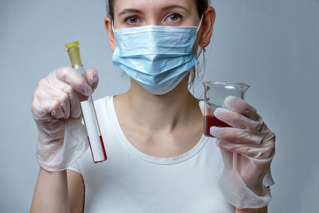 Una enfermera con una máscara protectora y guantes realiza pruebas en un recipiente médico.