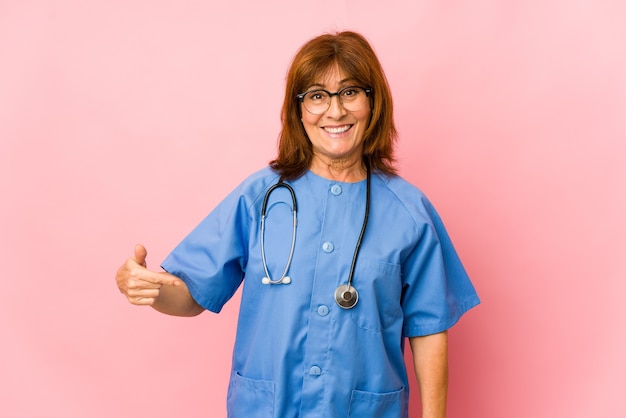 Enfermera de mediana edad mujer aislada persona apuntando con la mano a un espacio de copia de camisa, orgulloso y seguro