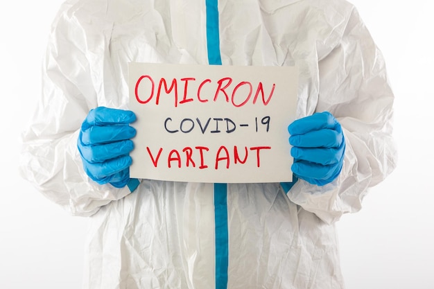 Enfermera médica con un PPE y guantes de látex con un cartel que dice: 'OMICRON VARIANT COVID-19'. Coronavirus, pandemia y concepto de salud.