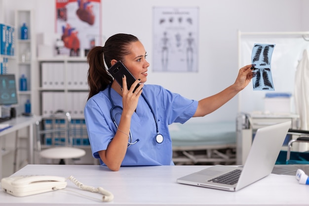 Enfermera médica con radiografía del paciente en la oficina del hospital. Radiólogo en uniforme médico sosteniendo y mirando rayos x, examen, hueso, médico, análisis, diagnóstico.