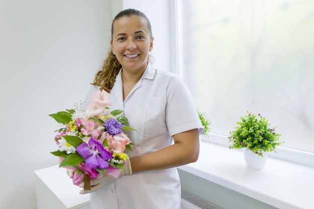 Enfermera mujer con ramo de flores.