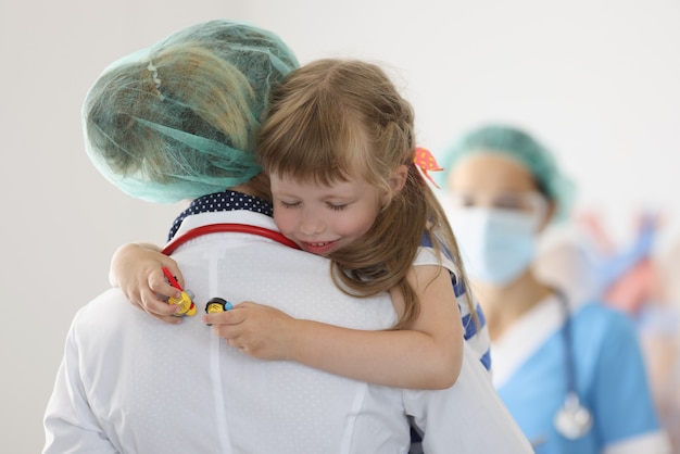 Foto enfermera con niña con los ojos cerrados en la clínica