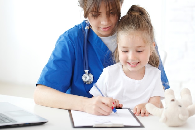 Enfermera y niño escribiendo registro médico.