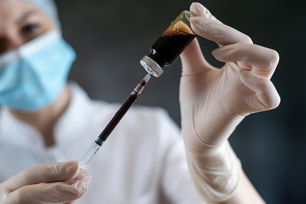 Enfermera o científica en uniforme médico completo preparando vacuna con jeringa para humanos aislados