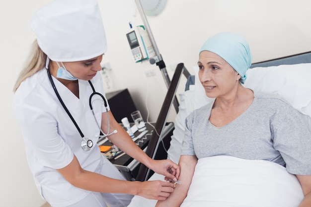 Una enfermera pone a una mujer con un cáncer con un gotero.