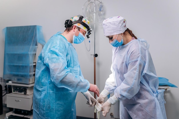 Enfermera poniéndose guantes médicos al cirujano antes de la operación Los médicos se preparan para la cirugía en el quirófano y se ponen un uniforme médico