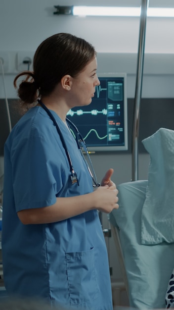 Enfermera revisando el oxímetro de un paciente enfermo en la sala del hospital