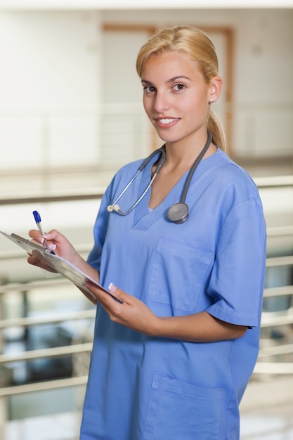 Enfermera rubia escribiendo en un portapapeles