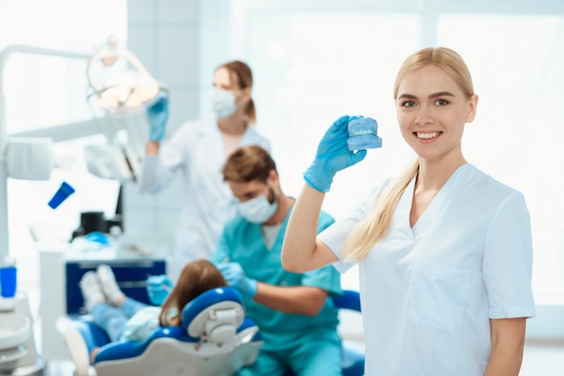 La enfermera sostiene el molde de la mandíbula con dentaduras postizas. Enfermera sonriendo