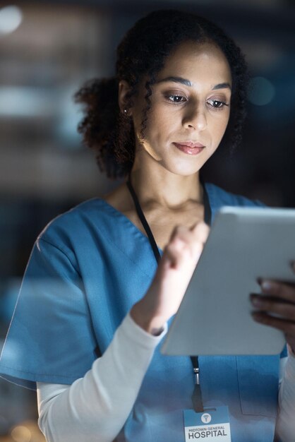 Enfermera de tableta médica y mujer negra en el hospital trabajando hasta tarde en investigación de telesalud o consulta en línea Atención médica técnica o médica con tecnología para aplicación de bienestar en la clínica por la noche