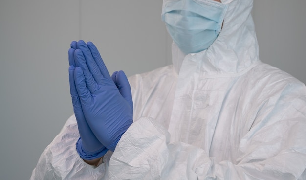 Una enfermera en traje de protección PPE rezando durante la pandemia causada por Covid19.