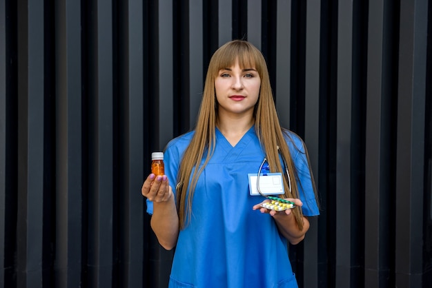 La enfermera en uniforme azul tiene pastillas en la pared gris. Concepto médico.