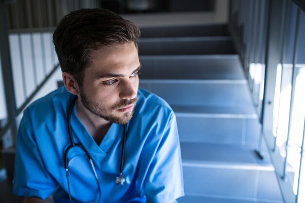 Enfermero pensativo sentado en la escalera