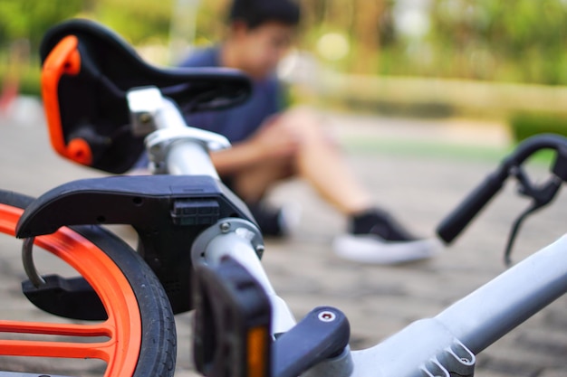 Enfoca la imagen de la bicicleta que cae y desdibuja a una persona detrás que resultó herida por la caída de una bicicleta en el parque