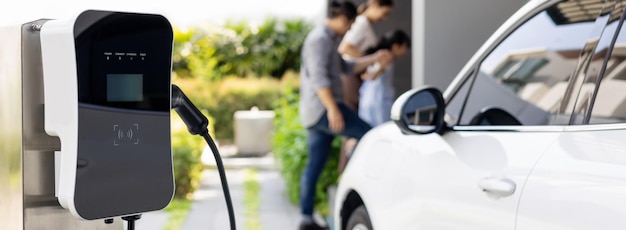 Enfocar la estación de carga doméstica para la familia progresiva de desenfoque de automóviles EV en segundo plano