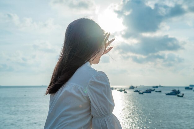 Enfocar la vista posterior de una chica asiática feliz levanta las manos frente a la playa en el concepto de Vung Tau Travel