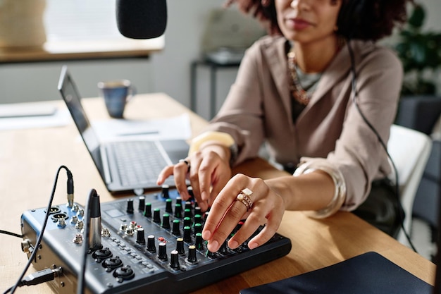 Foto enfoque en la mano de una mujer joven girando las consolas de la placa de sonido