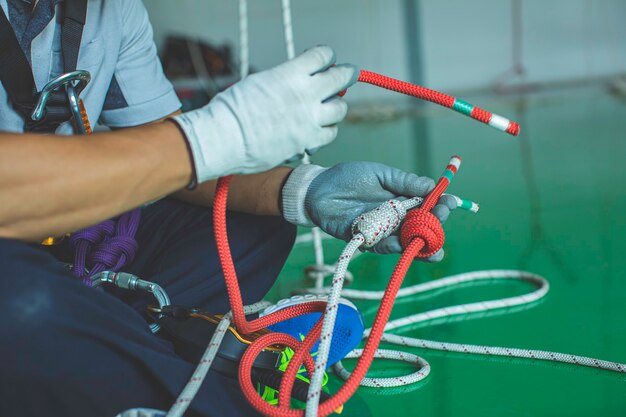 Enfoque de primer plano equipo de nudo de cuerda de enganche masculino formación acceso por cuerda en el trabajo en alto