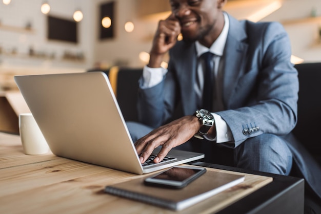 Enfoque selectivo de apuesto hombre de negocios afroamericano usando laptop en café