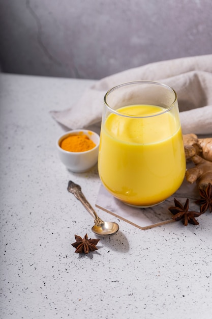 Enfoque selectivo. Bebida ayurvédica saludable leche de almendras doradas o café con leche de calabaza y cúrcuma con cúrcuma en polvo sobre fondo blanco. Copie el espacio Bebida de desintoxicación natural asiática de moda con especias para veganos