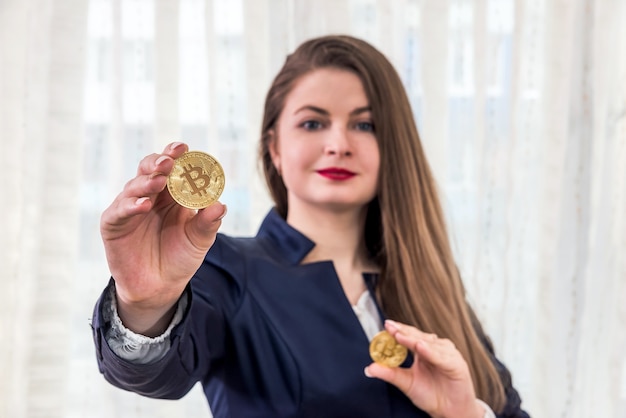 Enfoque selectivo en bitcoin dorado en manos de mujer