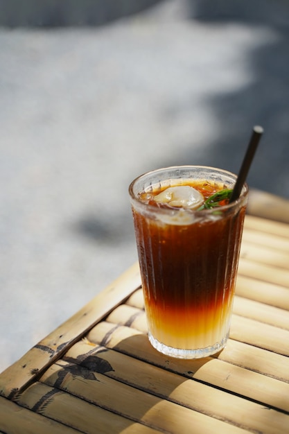 Foto enfoque selectivo café negro largo mezclado con lychee sobre fondo de naturaleza. menú de bebidas heladas de bebida de verano para un día relajante.