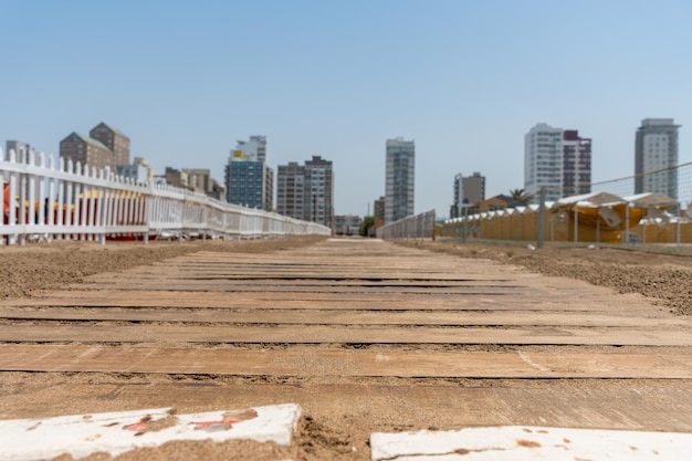 Enfoque selectivo de un camino de madera en la playa con edificios de la ciudad al fondo