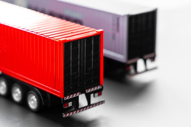 Enfoque selectivo de camiones de contenedores sobre fondo blanco, estacionamiento de camiones de contenedores de remolque en el almacén, empresa de transporte de transporte y logística comercial global.